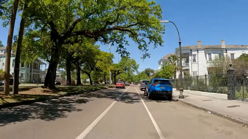 Tree-lined Esplanade Avenue in New Orleans with historic homes and cars parked along the street