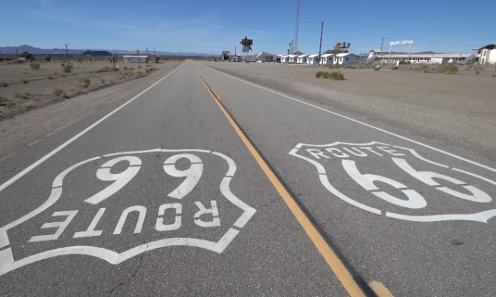 Route 66 highway featuring white painted lines stretching into the distance under a clear blue sky