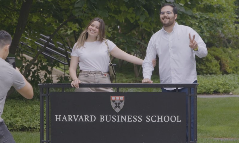 Harvard Business School students pose for photos with a professional photographer on campus