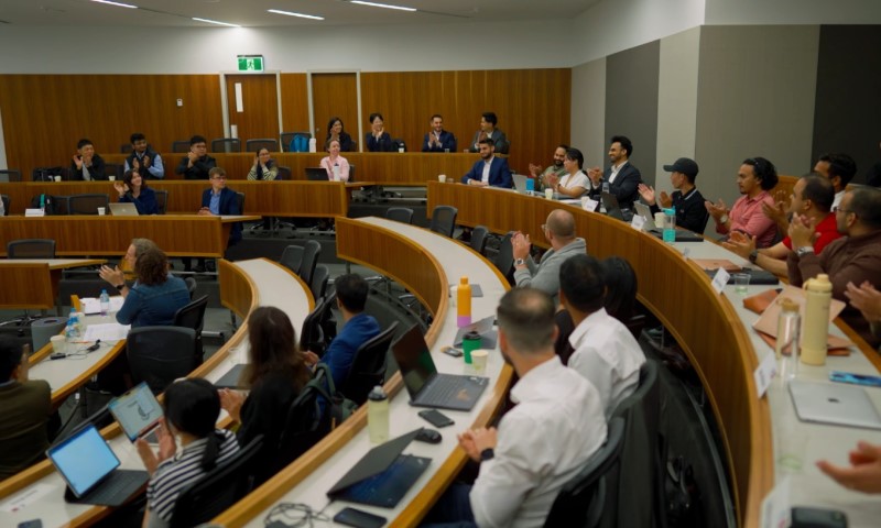 A diverse group of people attentively seated in a lecture hall, facing a speaker at the front