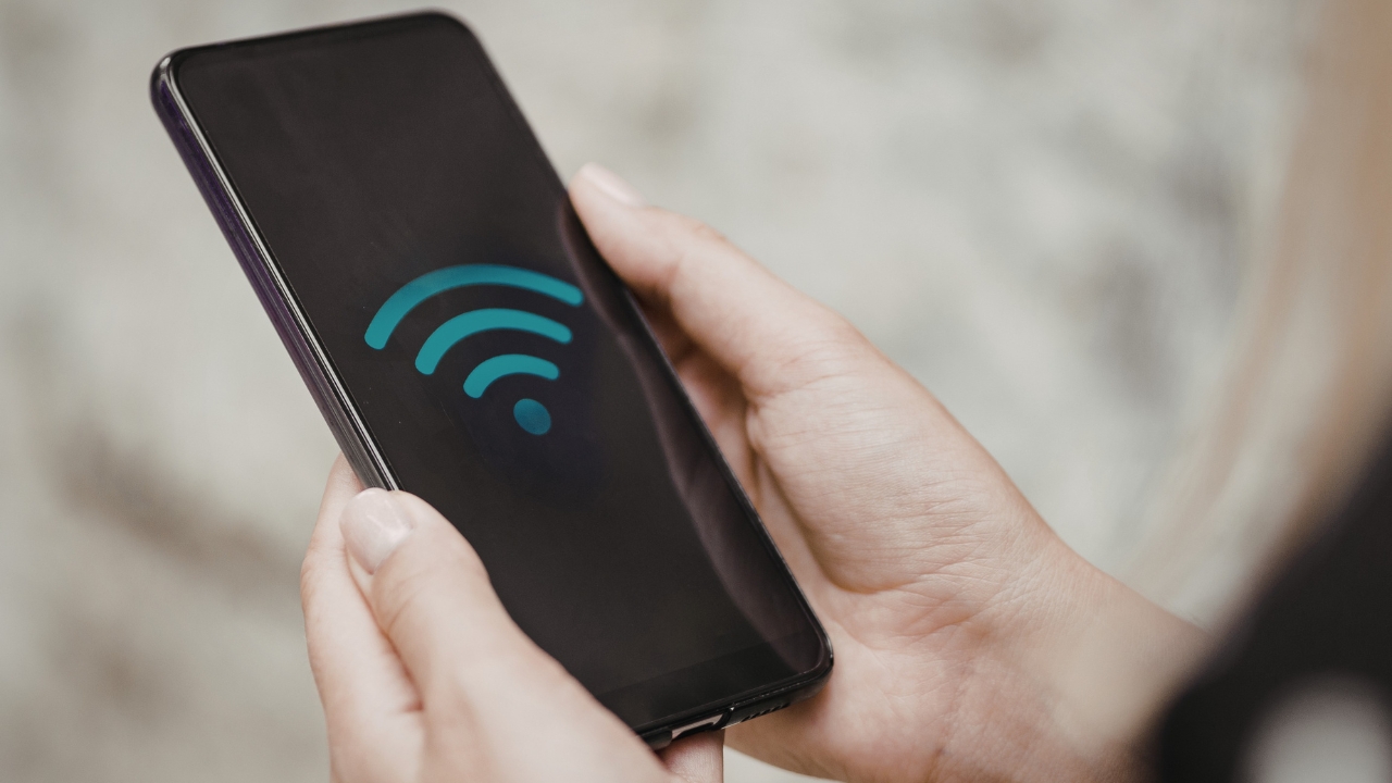 Person holding a smartphone displaying a Wi-Fi symbol on the screen