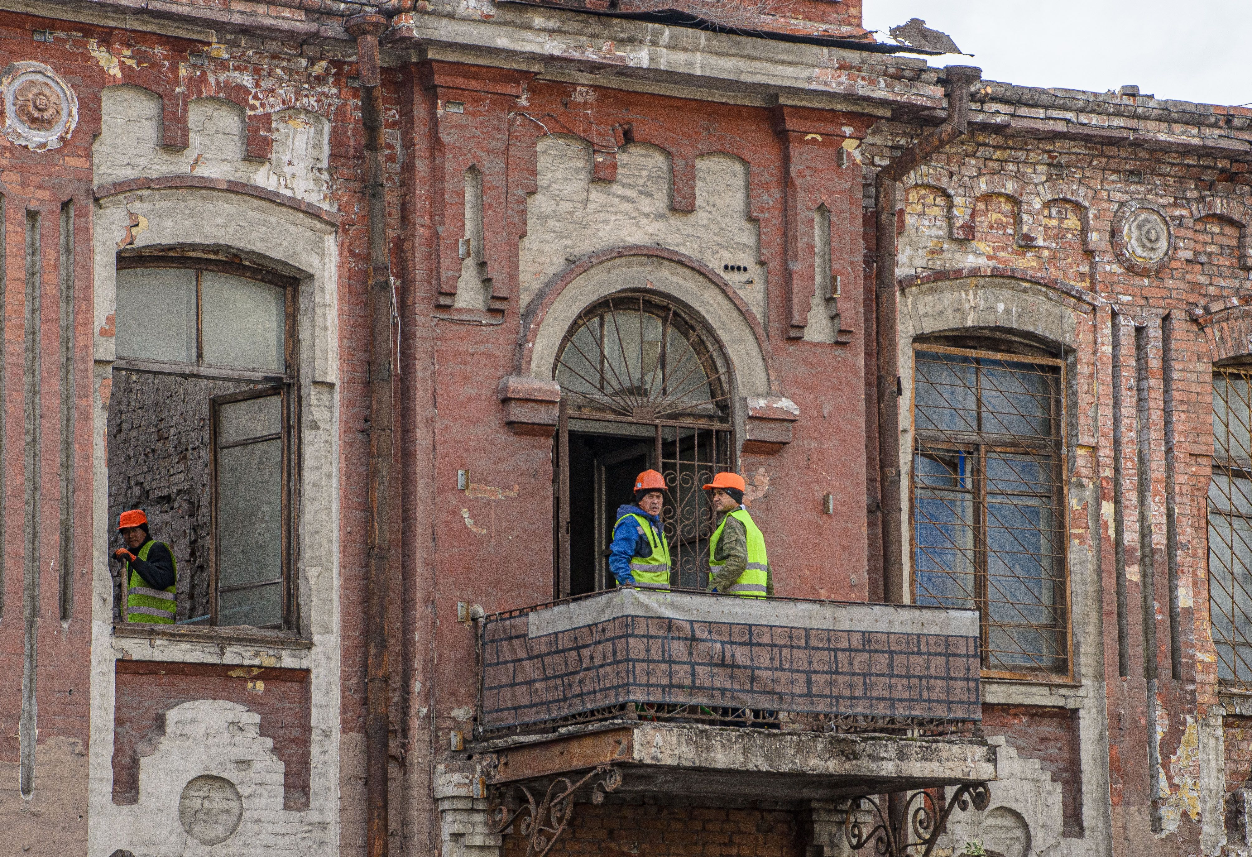 Construction workers renovating an old brick building with traditional architecture
