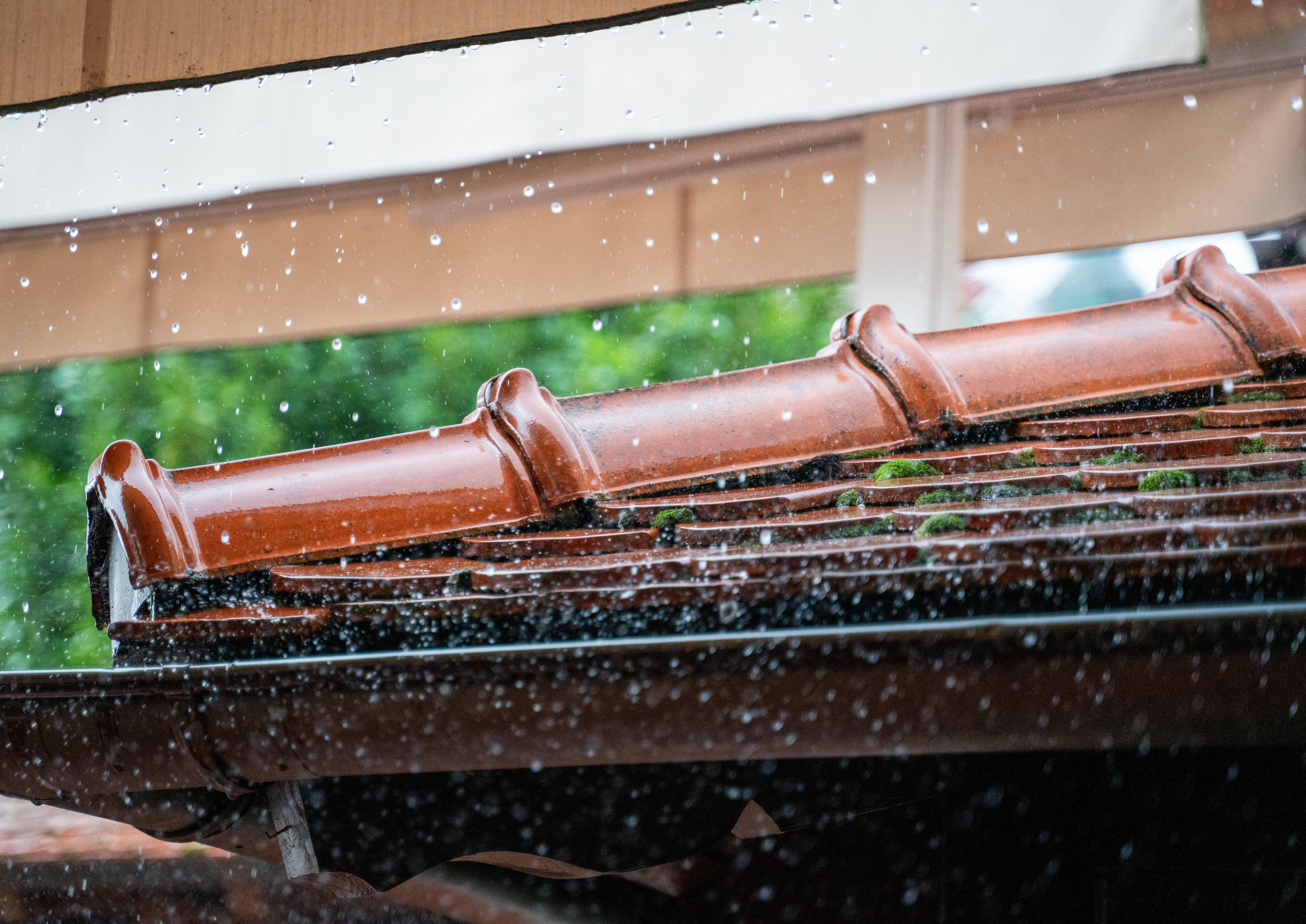 Rain droplets cascading off a terracotta roof on a rainy day