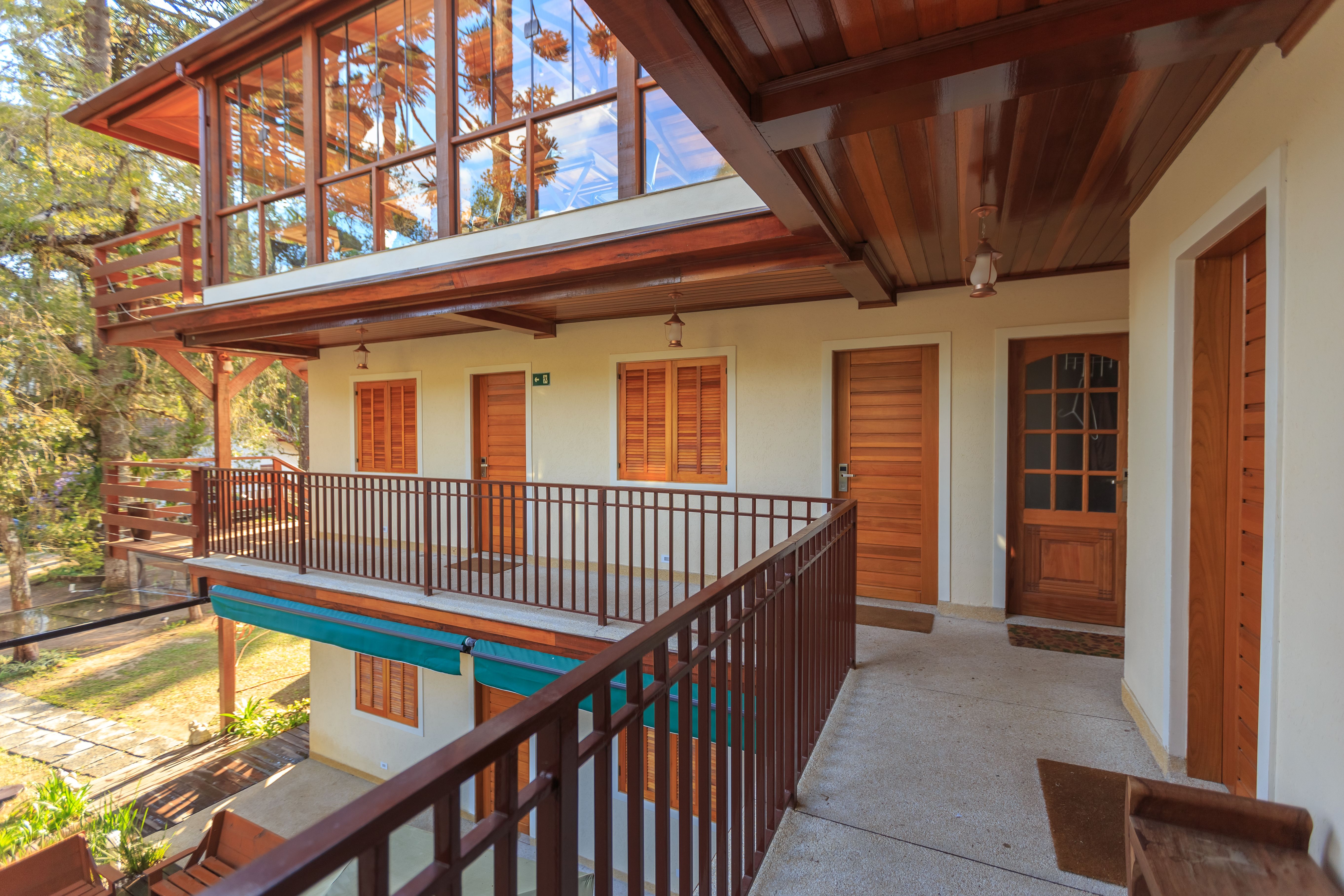 Villa exterior with wooden balcony and large windows overlooking natural views