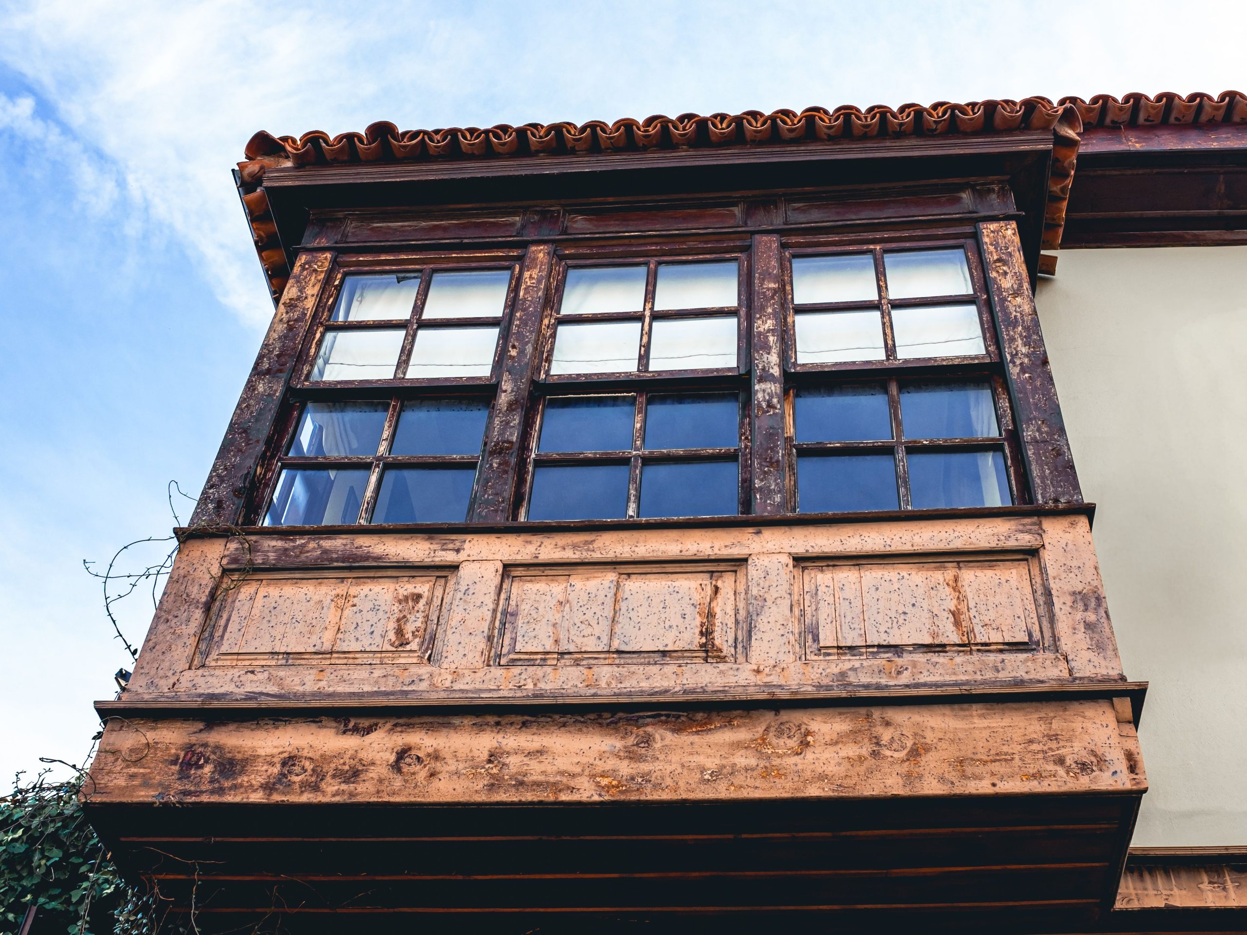 Vintage wooden balcony with rustic windows under a clear blue sky